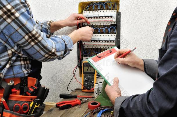 年幼的技术人员电工和工程师检查指已提到的人电压关于一