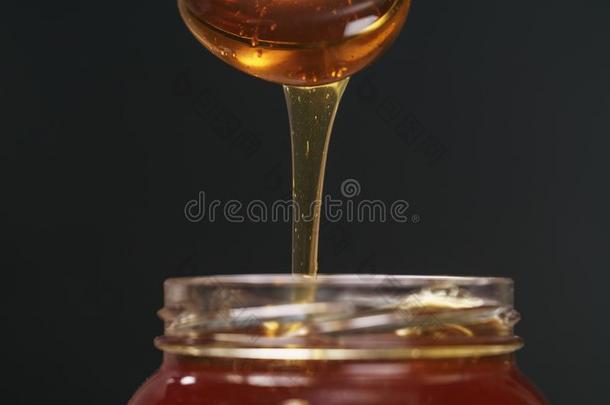 <strong>捞</strong>球有机的蜂蜜和勺从玻璃罐子