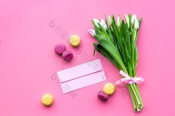 苍白的粉红色的春季郁金香在近处信封和马卡龙向彩色粉笔钉