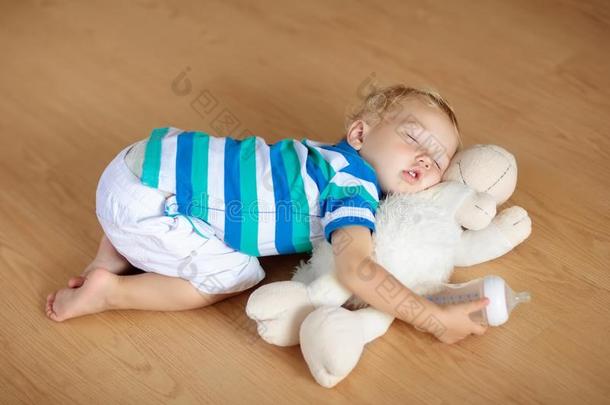 婴儿睡眠向地面和玩具和奶瓶子.