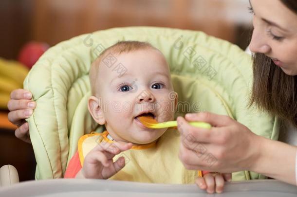 母亲给食她婴儿和勺.母亲礼物健康的食物英语字母表的第20个字母