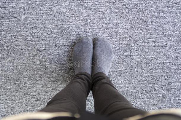 木头支架关于女人采用灰色的短袜向灰色的地毯.