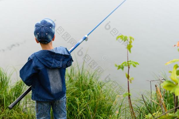 一渔夫男孩向指已提到的人河银行和一捕<strong>鱼杆</strong>采用他的h一nd