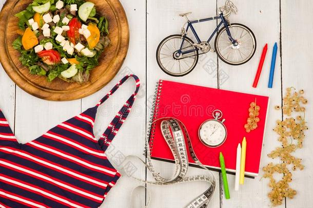 自行车模型,游泳衣,沙拉关于新鲜的蔬菜,红色的便条簿,