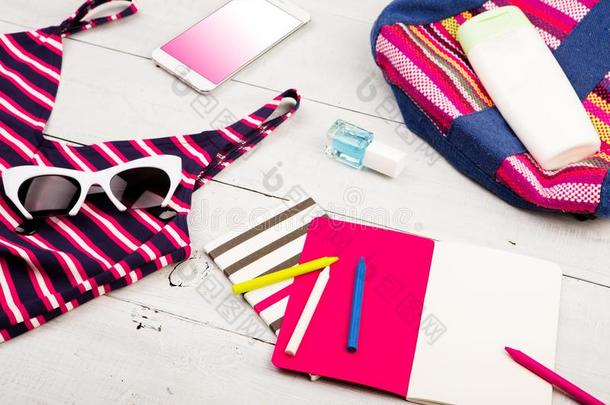 富有色彩的有条纹的袋,游泳衣,聪明的电话,太阳镜和笔记