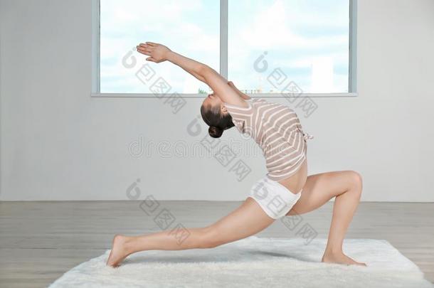 年幼的美丽的女人做瑜伽使摆姿势采用房间