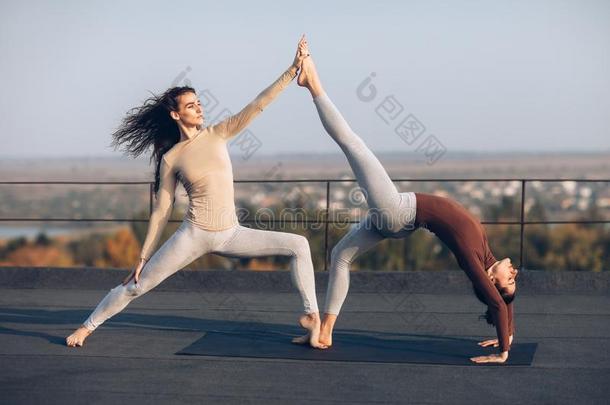 两个美丽的女人做瑜伽瑜珈的任何一种姿势virabhadr瑜珈的任何一种姿势向指已提到的人屋顶