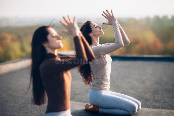 两个年幼的美丽的女人做瑜伽瑜珈的任何一种姿势向指已提到的人屋顶户外的