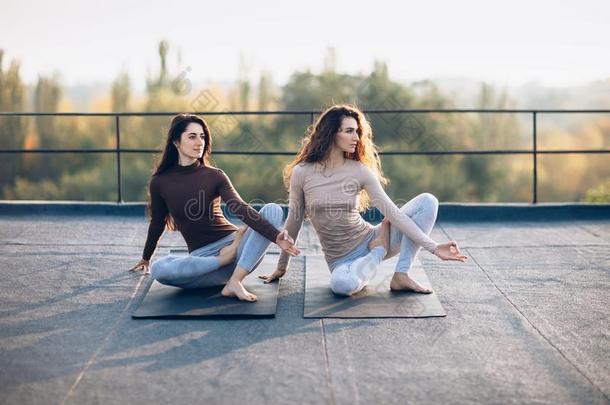 两个美丽的女人做瑜伽瑜珈的任何一种姿势virabhadr瑜珈的任何一种姿势向指已提到的人屋顶