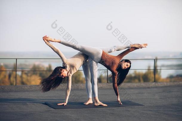 两个美丽的女人做瑜伽瑜珈的任何一种姿势阿德哈Chandr瑜珈的任何一种姿势