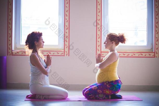 红色的上端怀孕的年幼的女人向瑜伽班和指导者