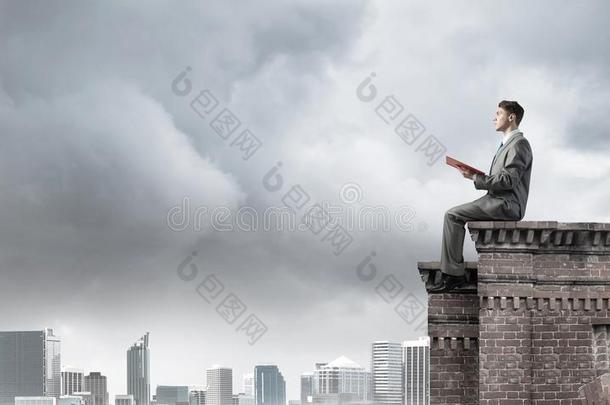 男人向屋顶边阅读书和城市风光照片在背景