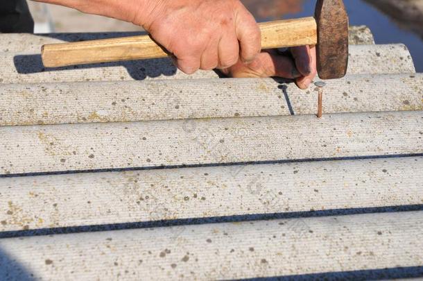 盖屋顶的人替换被损坏的石棉瓦片.修理石棉屋顶.酸的净输入