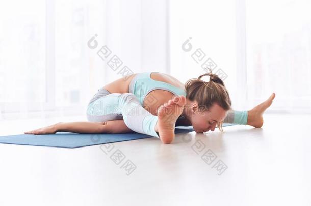 美丽的年幼的女人练习瑜伽瑜珈的任何一种姿势Kurm瑜珈的任何一种姿势-乌龟
