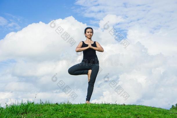 女人开业的瑜伽轻松采用自然和蓝色天背景