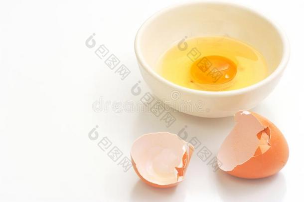 破碎的蛋壳和鸡蛋蛋黄采用碗和空间白色的后台