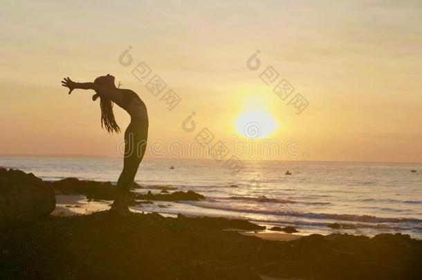 轮廓瑜伽练习在日落.扬Young的变体女人做瑜伽锻炼