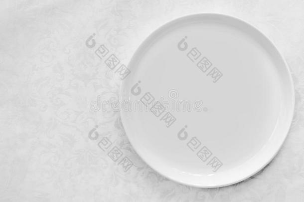 空的白色的盘子越过凸<strong>花纹</strong>织物桌布顶看法