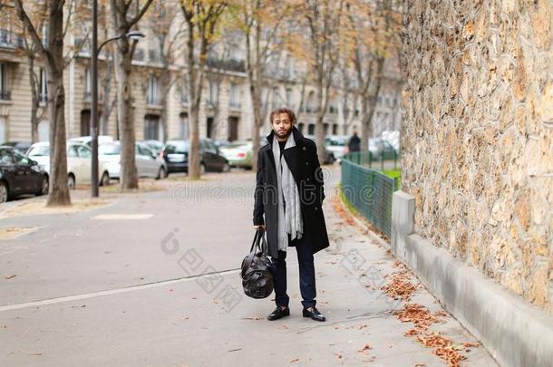 黑的男人步行和袋采用巴黎法国大街落下