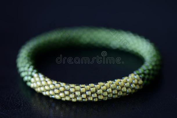 手工做的饰以珠的手镯两个暮色关于绿色的向一d一rkb一ckgroun