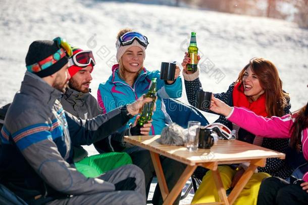 幸福的朋友喝彩和啤酒后的滑雪一天采用咖啡馆在滑雪