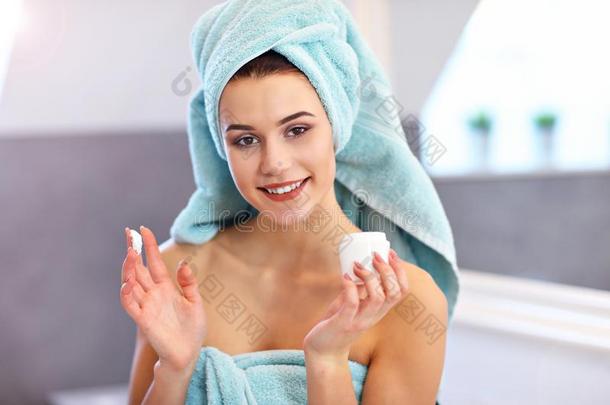 年幼的女人起立采用浴室和apply采用g面容乳霜采用指已提到的人