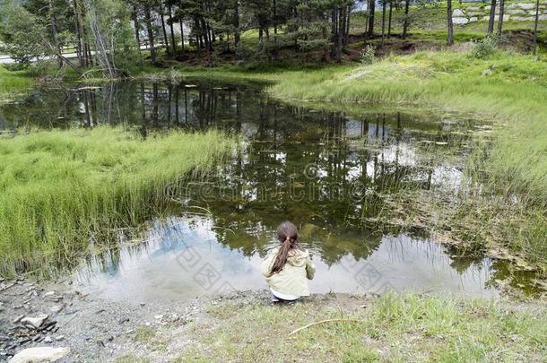 小的女孩演奏和一粘贴采用一池塘