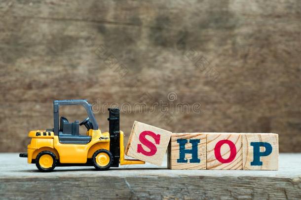 黄色的玩具铲车拿住信块英文字母表的第19个字母向完全的单词商店