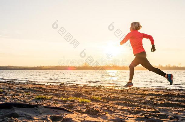 女人海滩跑步在日出,湖海岸线