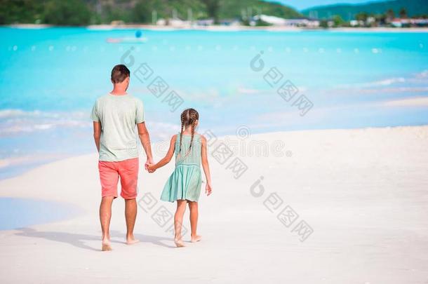 幸福的父亲和他的值得崇拜的小的女儿在热带的海滩