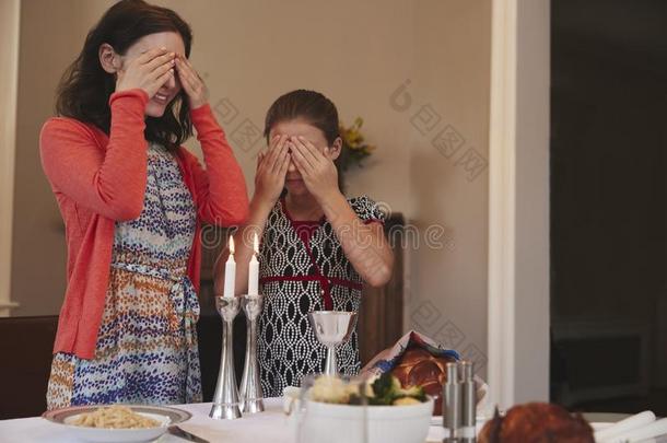 犹太人的女孩和母亲遮盖眼睛向背诵安息日祝福