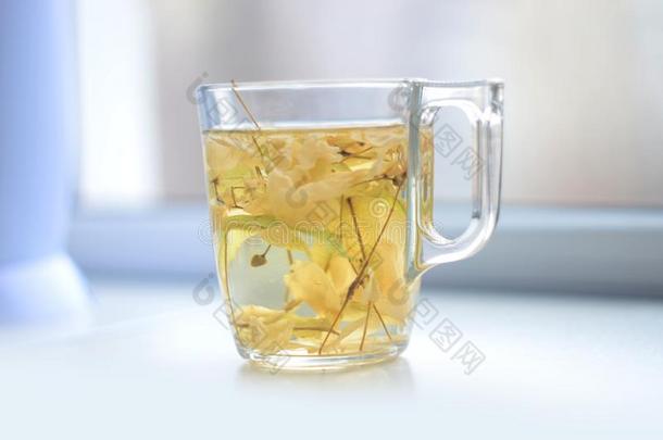 玻璃杯子和调制菩提树草绿色的茶水向指已提到的人窗沿