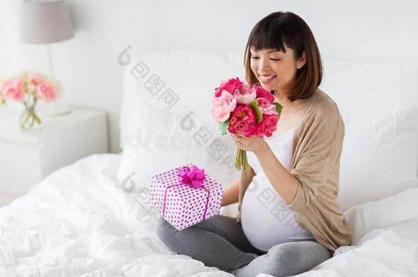 幸福的亚洲人怀孕的女人和赠品和花