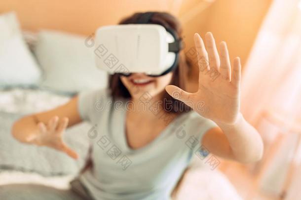 漂亮的十几岁的女孩一次向床和测试VirtualReality虚拟现实戴在头上的耳机或听筒