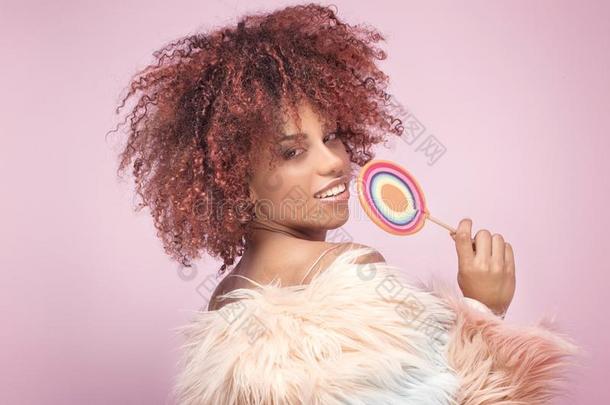 流行的非洲式发型女人和棒棒糖向粉红色的背景.