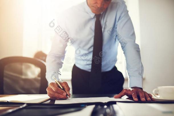 商人倾向越过他的办公室书桌签署文档