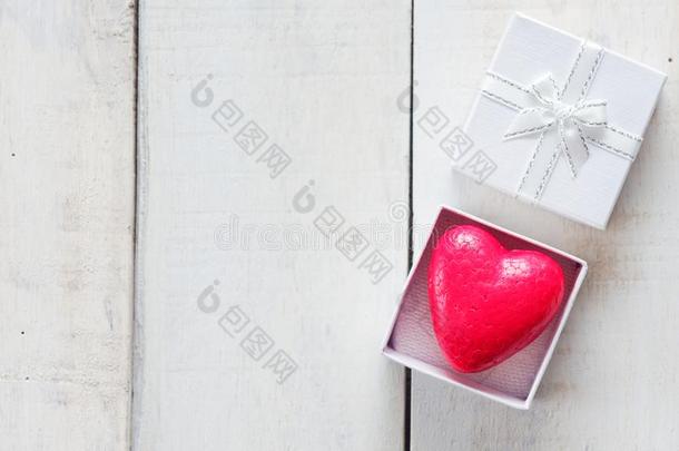 红色的心里面的白色的赠品盒越过白色的木制的背景
