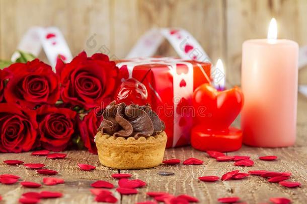 纸杯蛋糕和樱桃采用前面关于花束关于红色的玫瑰和cadles