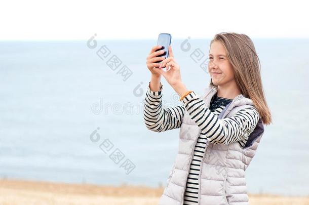 年幼的女孩采用小麦田tak采用g照片在旁边智能手机