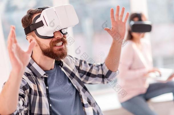 有魅力的有趣的男人令人难于忍受的向抓住VirtualReality虚拟现实物体