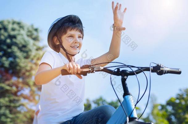 快乐的男孩招呼某人在期间骑马自行车