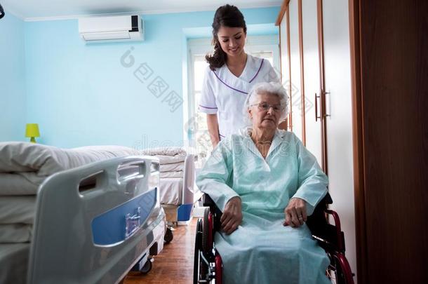 护理家,护士进行在外面和老的女人在轮椅