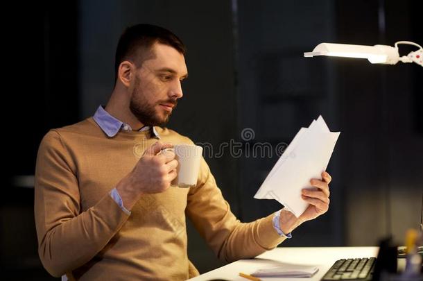 男人和文件和咖啡豆工作的在夜办公室