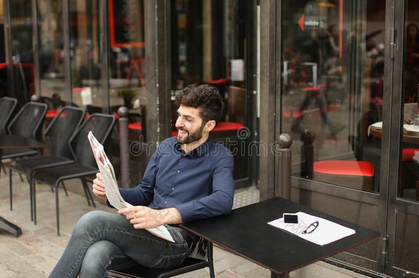 欢乐的男人阅读报纸在咖啡馆和眼镜和斯马特福