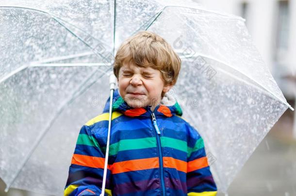 小的亚麻色的小孩男孩向道路向学校步行在的时候雨夹雪或雹,雨