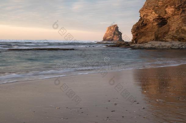 沙的海滩采用软的富有色彩的日落和悬崖和岩石飘零双燕jointuse联合使用