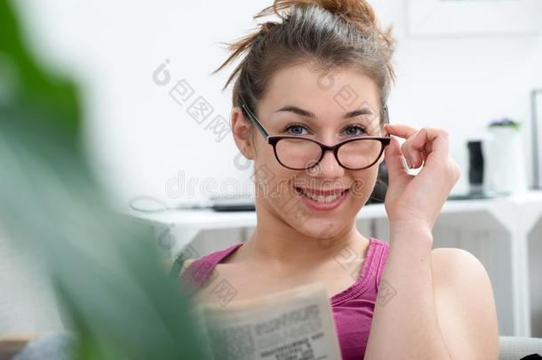 年幼的和微笑的女人和眼镜,阅读报纸