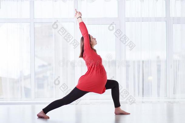 年幼的美丽的怀孕的女人做瑜伽瑜珈的任何一种姿势Virabhadr瑜珈的任何一种姿势1