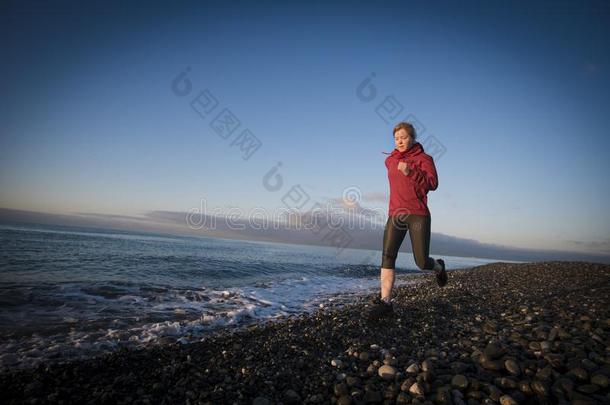 成熟的女人赛跑者跑步向日出海滨.健康的生活方式