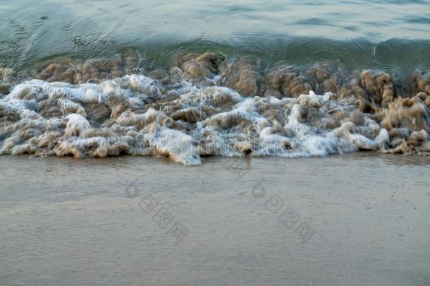 波浪旋转的在海滨越过棕色的海滩沙
